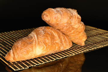 Homemade croissants, close-up, on a black background.