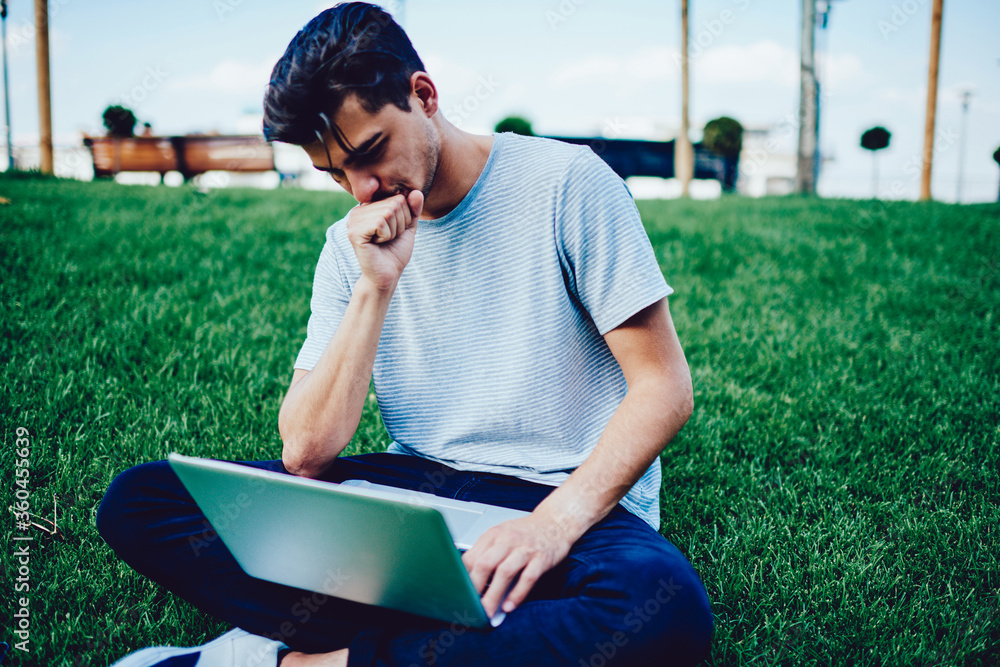 Poster young hipster guy worried about problem with software on laptop computer while installing new applic