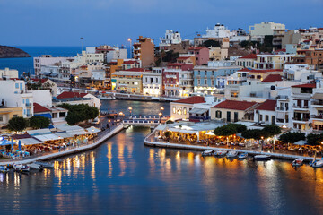 Fototapeta na wymiar A panorama of the harbor city of Agios Nikolaos. View of the night sea, interesting landscapes, colorful houses, a coast view from the cafe. A popular tourist resort in the Greece.