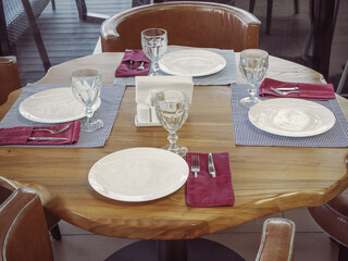Closeup photo of an unusual shaped table with cutlery and fragments of leather armchairs