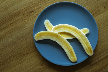 Peeled bananas cut on a clay plate on the table