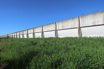 White cement noise barrier with green grass