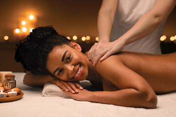 Obraz na płótnie Canvas Cheerful african woman enjoying relaxing body massage