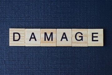  text on word damage from gray wooden letters on a black background