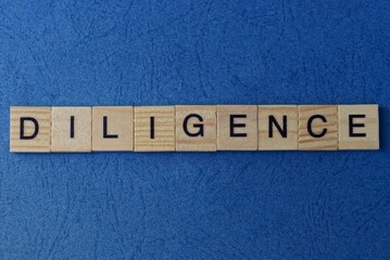  text on gray word diligence in small wooden letters with black font on a blue background