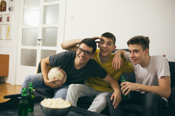 teenager boys having fun at home, watching soccer game on tv