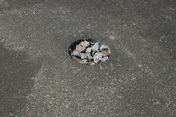 one round pothole pit on the gray asphalt of the road