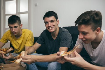 teenager boys eating pizza at home