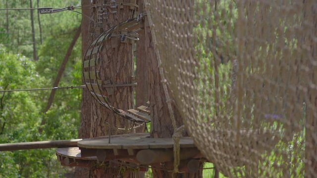 A little boy in an adventure park. He wears a safety harness. He climbs on a high rope trail. Outdoor amusement center with climbing activities consisting of zip lines and all sorts of obstacles