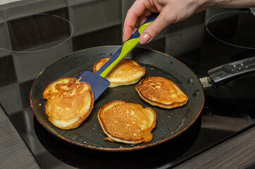 Pancakes are fried in a pan on an induction stove	
