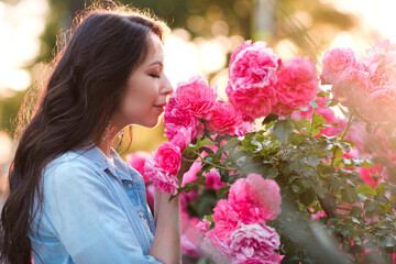Fototapeta premium Beautiful woman 25-26 year old holding pink rose flowers in garden closeup. Summer season. 20s.