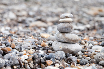 Fototapeta na wymiar Grey pebble stones pyramid on the beach. Concept of zen, stability, harmony, balance. Close up, macro. front view