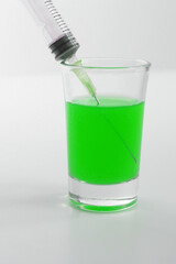 Syringe with green liquid on the white background. Syringe and glass on a white background. 