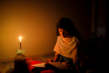 A young girl studying at home with candlelight after electricity load shedding at Dhaka City, Bnagladesh. Blackout. Electricity Problem.