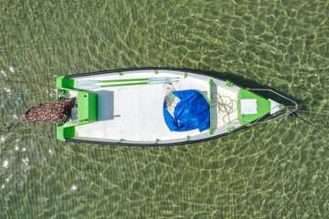 Small Fishing Boat anchored in a shallow lagoon, with packed Fish net onboard, Aerial image.