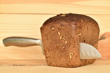 Black cereal bread, macro, on a background of natural wood.