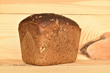 Black cereal bread, macro, on a background of natural wood.