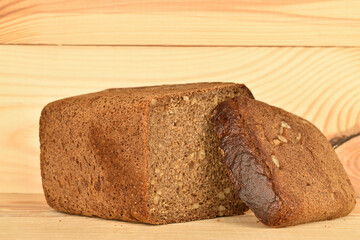 Black cereal bread, macro, on a background of natural wood.
