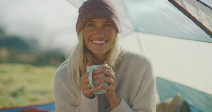 Happy attractive young woman drinking warm tea camping in the mountains, camping adventure lifestyle outdoors