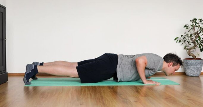 young man doing her workout at home - pushup exercise