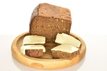 Slices of black cereal bread with butter on a white background.