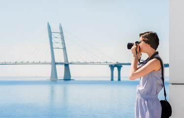 Girl tourist photographs the bridge and the sea. Photographer while shooting a landscape