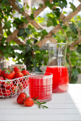 Strawberry lemonade, red drink with ripe berries and rosemary, on a white wooden table. Summer refreshing drink. Selective focus.