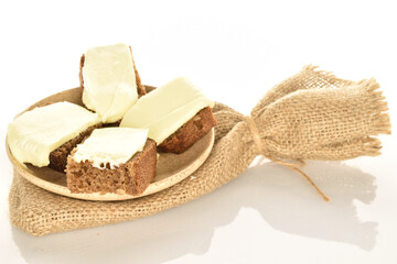 Slices of black cereal bread with butter on a white background.