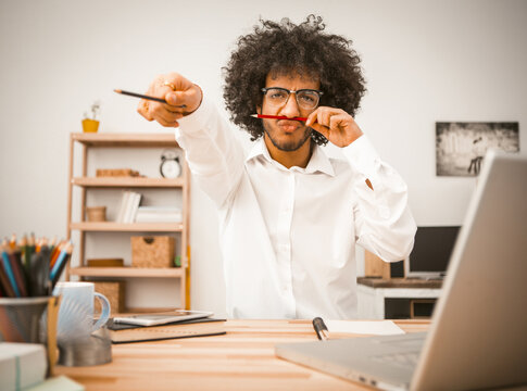 Funny Young Man Hase Fun Holding Pencil To His Nose Like Mustache. Work Break Concept. Toned Image.