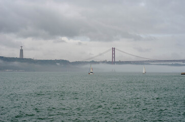 25th of April Suspension Bridge over the Tagus river in Lisbon, Portugal Havy rainy clouds and fog at Ponte 25 de Abril, Lisboa, Portugal