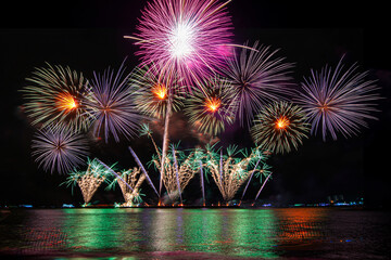 Amazing beautiful colorful fireworks display on celebration night, showing on the sea beach with...
