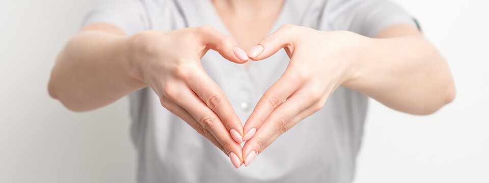 Close up of female hands of doctor making heart shape. Romantic concept.