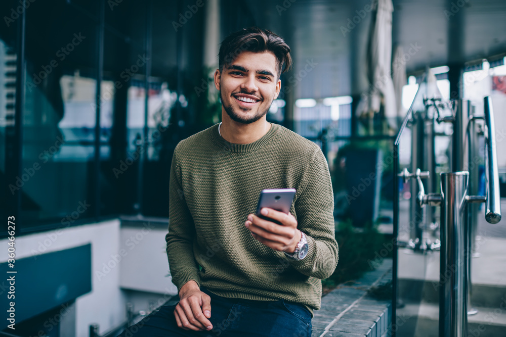 Poster portrait of cheerful handsome male using mobile phone and wireless internet for chatting and network