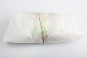 isolated close up shot of a sandwich wrapped in a baking paper wrap package with a green ribbon, on a white background