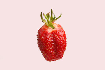 isolated close up detailed side view shot of a delicious vibrant red strawberry on a pink background