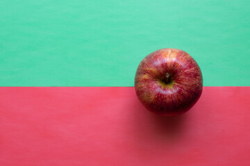 Single red apple isolated on half green and half red background. Pop art style. Top down view flat...