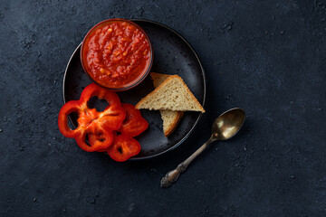 Fresh Ajvar made from tomatoes and paprika on a black background. Homemade aivar