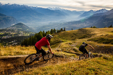 CRANS MONTANA, SWITZERLAND. Two mountain bikers riding a twisty trail in the purpose built bike...