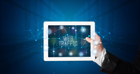 Young business person working on tablet and shows the digital sign: WEB TRAFFIC