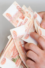 Men's hands hold a large amount of money with Russian banknotes of five thousand rubles