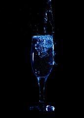 Splashes and drops of water in a glass are isolated on a black background.