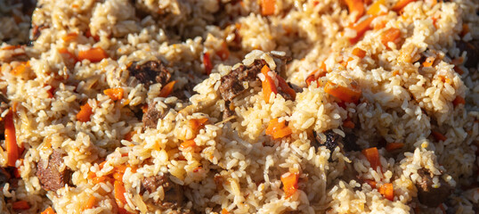 Pilaf with rice is cooked on a cast-iron cauldron.