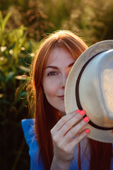 Girl smiles, covers her face with a hat