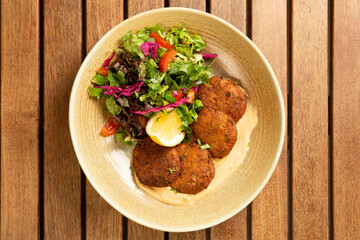 Top view of falafel with salad and hummus in a bowl