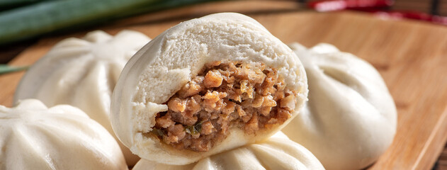 Delicious baozi, Chinese steamed meat bun is ready to eat on serving plate and steamer, close up,...