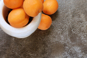 Apricots and space for text. Fruit with space for text. Abstract brown background for design. Apricots in marble mortar 