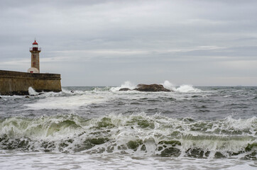 Fototapeta na wymiar Lighthouse on a Porto city Portugal beach with dramatic waves of atlantic ocean