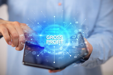 Businessman holding a foldable smartphone with GROSS PROFIT inscription, new business concept