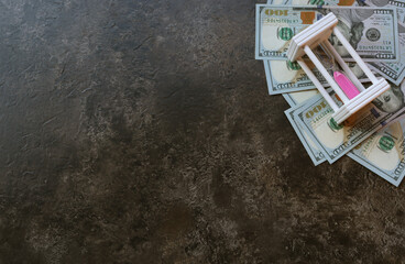 Banknotes and hourglass on a brown background with place for text. 100 dollar bills. Money. Business. Time is money
