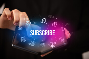 Businessman holding a foldable smartphone with SUBSCRIBE inscription, social media concept